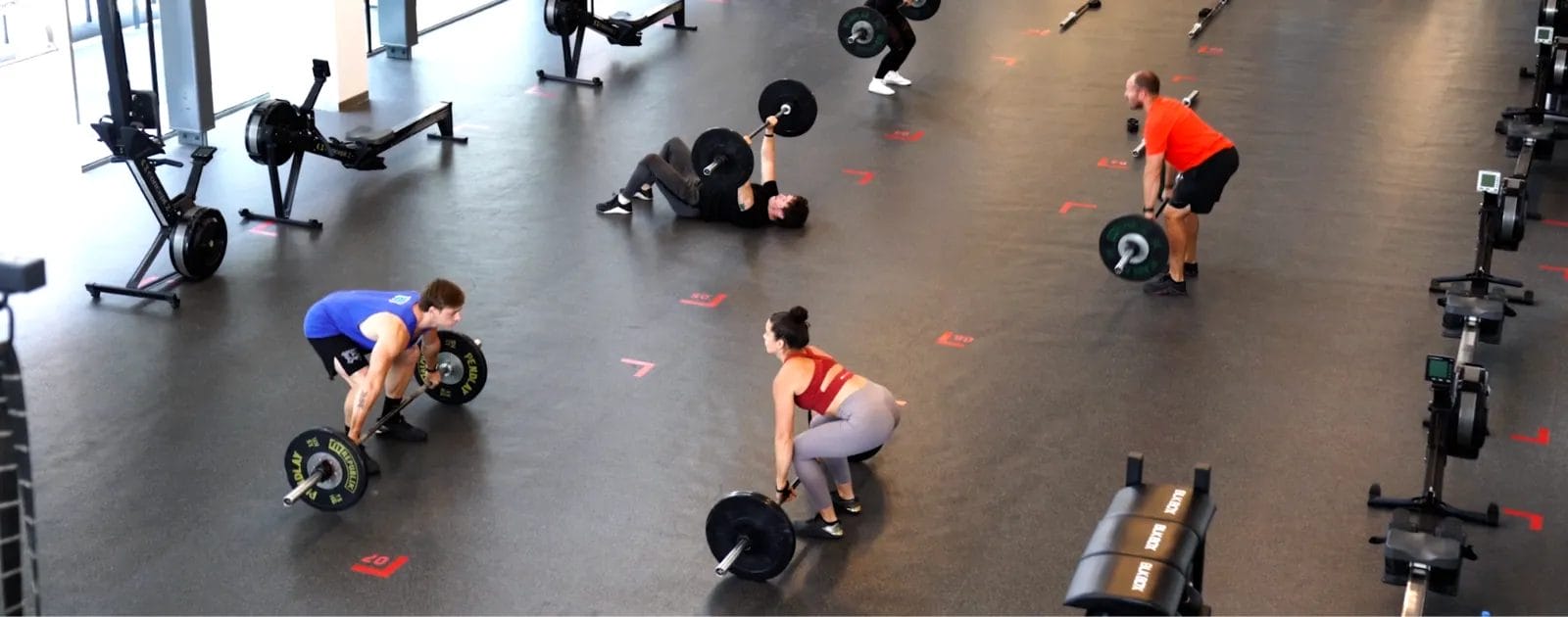 2 people are watching their coach and going to lift their weight