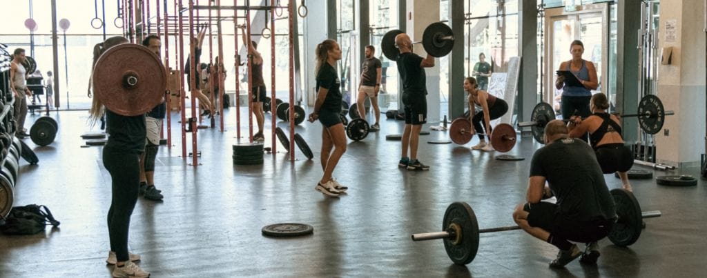 people are weightlifting as per coach's instructions