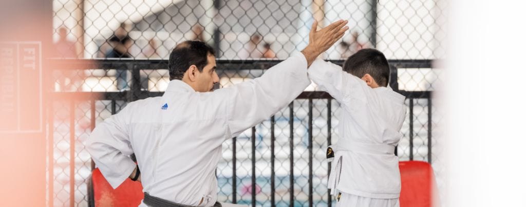 a kid is blocking karate attack from the trainer