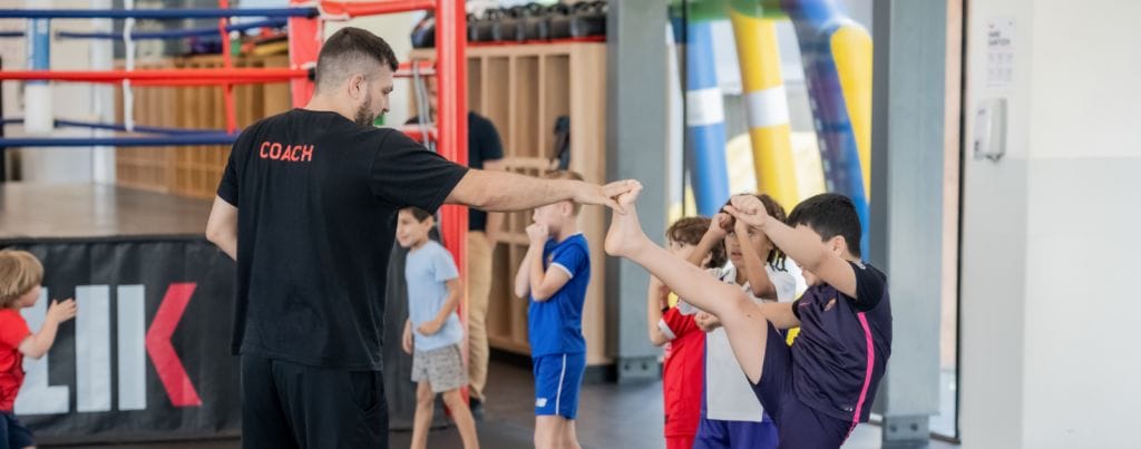 a coach is training stretching kicks for a kid